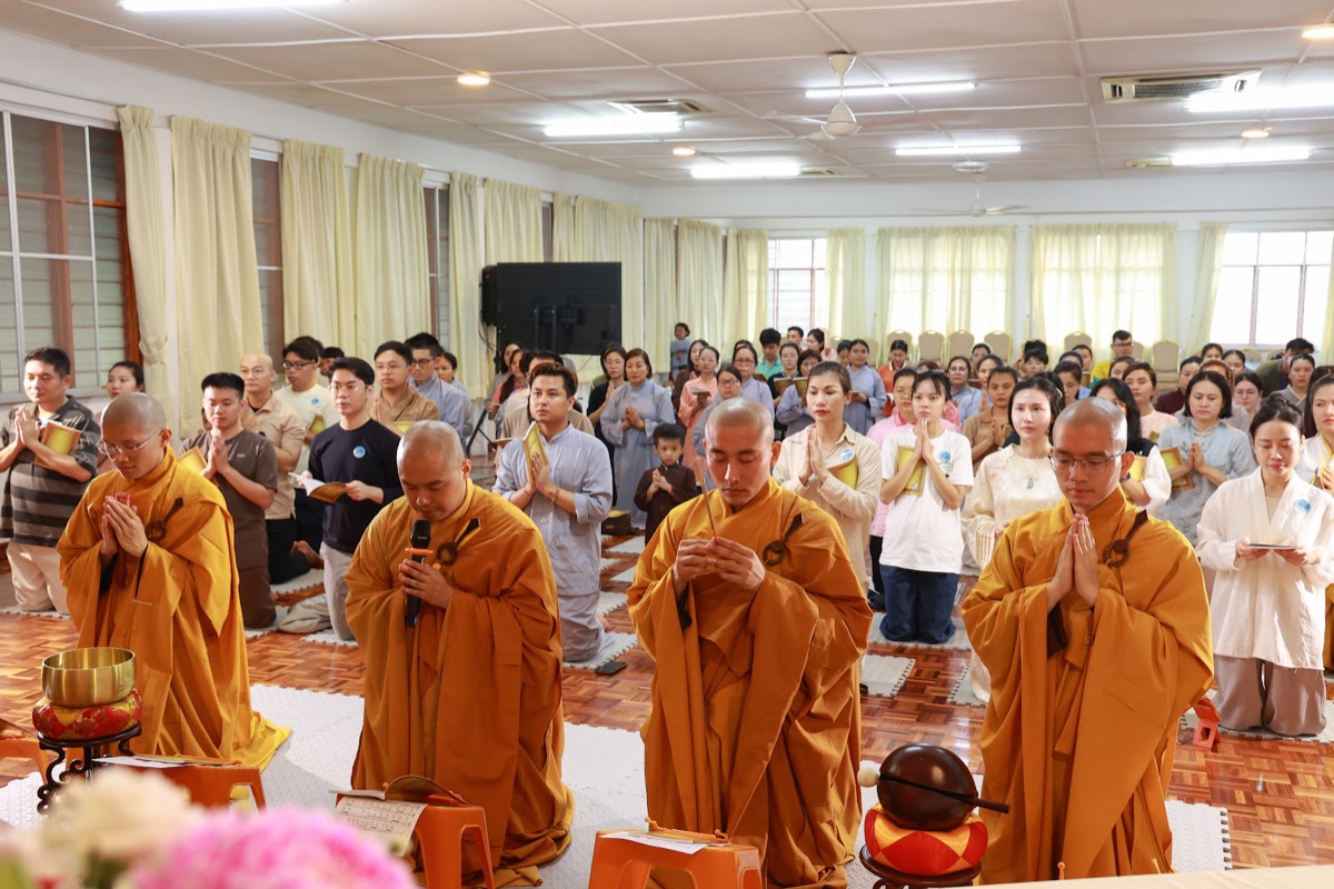 Venerable monks leading a chanting session with a full hall of participants